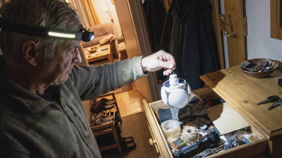 Dunkler Flur, eine Person mit Lampe vor dem Sicherungskasten